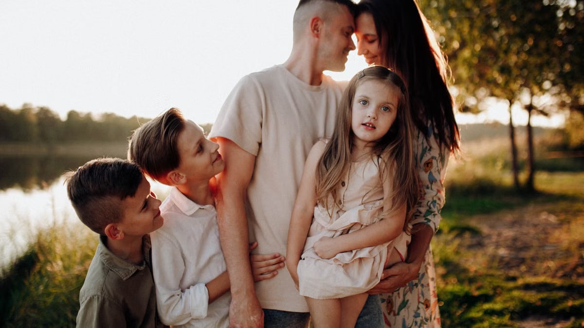 Family enjoying quality time together outdoors by the lake during sunset.